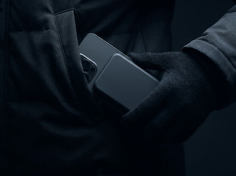A phone with the power bank attached being lifted out of a jacket pocket, still held firmly